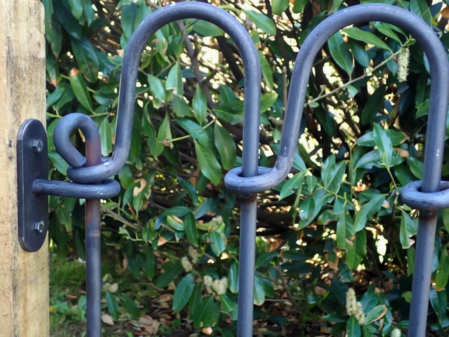 Obere Detailaufnahme: Steckzaun Vienna mit Wandhalter Eisen roh und Endstab auf Holzpfosten montiert